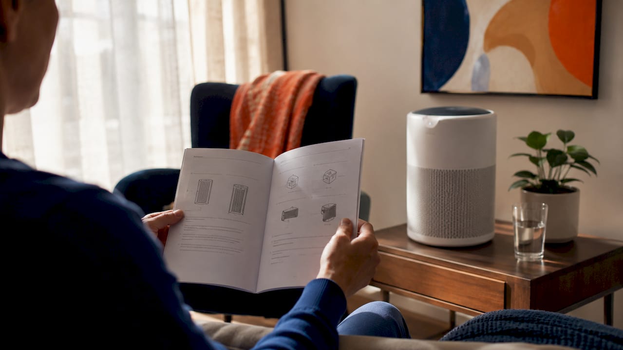 Hands reading air purifier manual in kitchen
