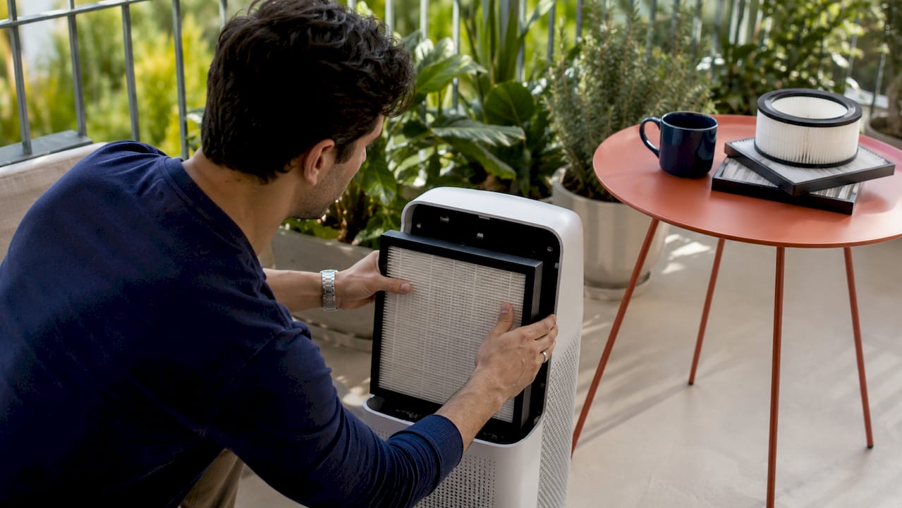Hands removing HEPA filter from air purifier unit