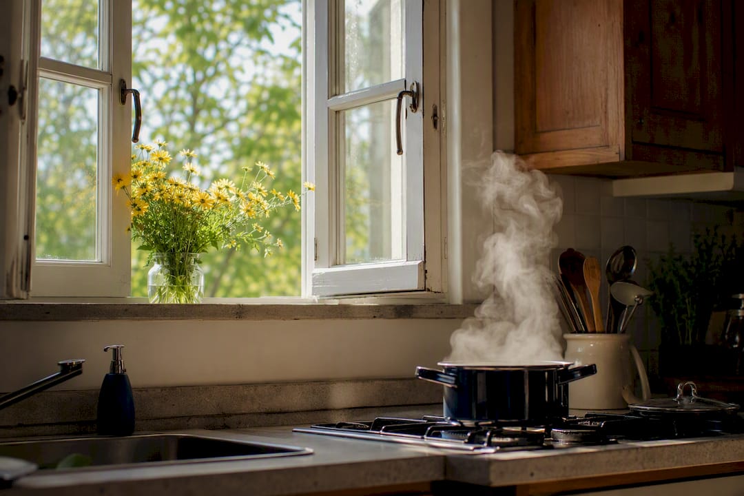 Open kitchen window with steam rising from stove