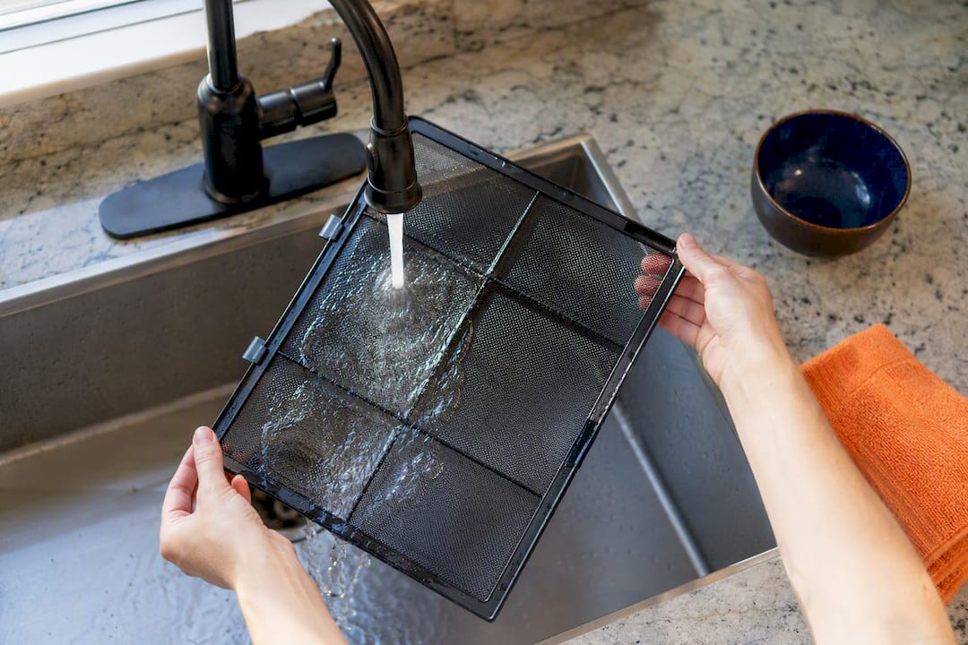 Hands rinsing a washable purifier prefilter